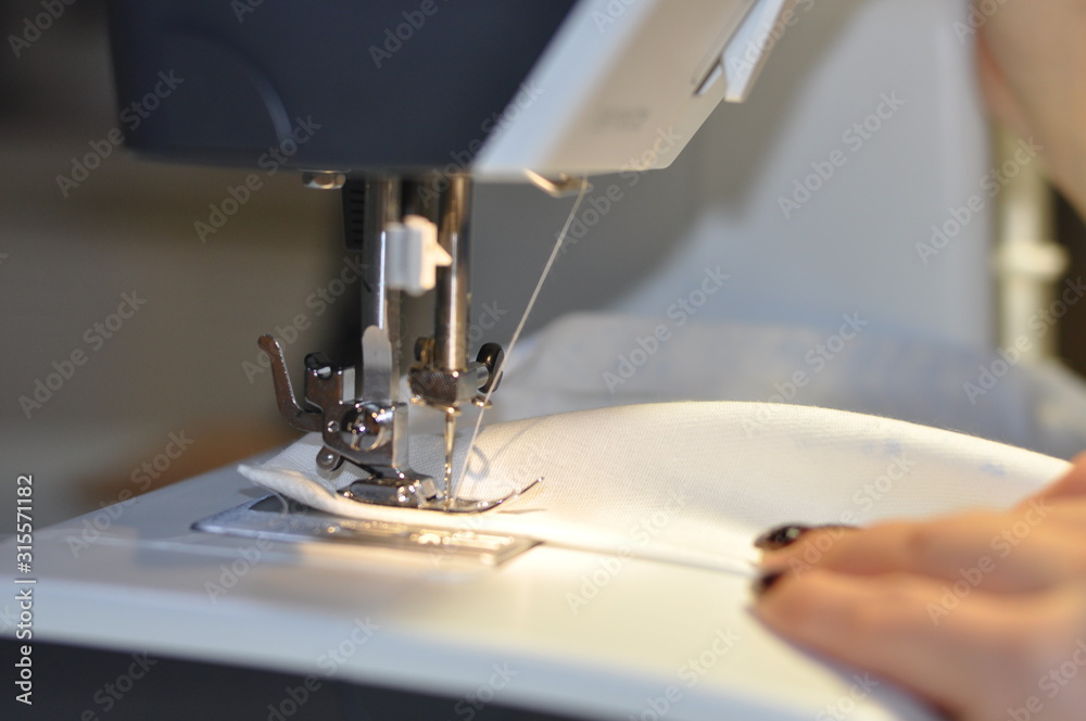 Sewing machine. At work, a girl with a beautiful manicure in her hands.
