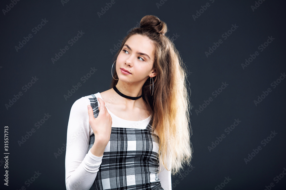 Young beautiful girl model in plaid dress portrait in Studio on dark background Young beautiful girl model in plaid dress portrait in Studio on dark background