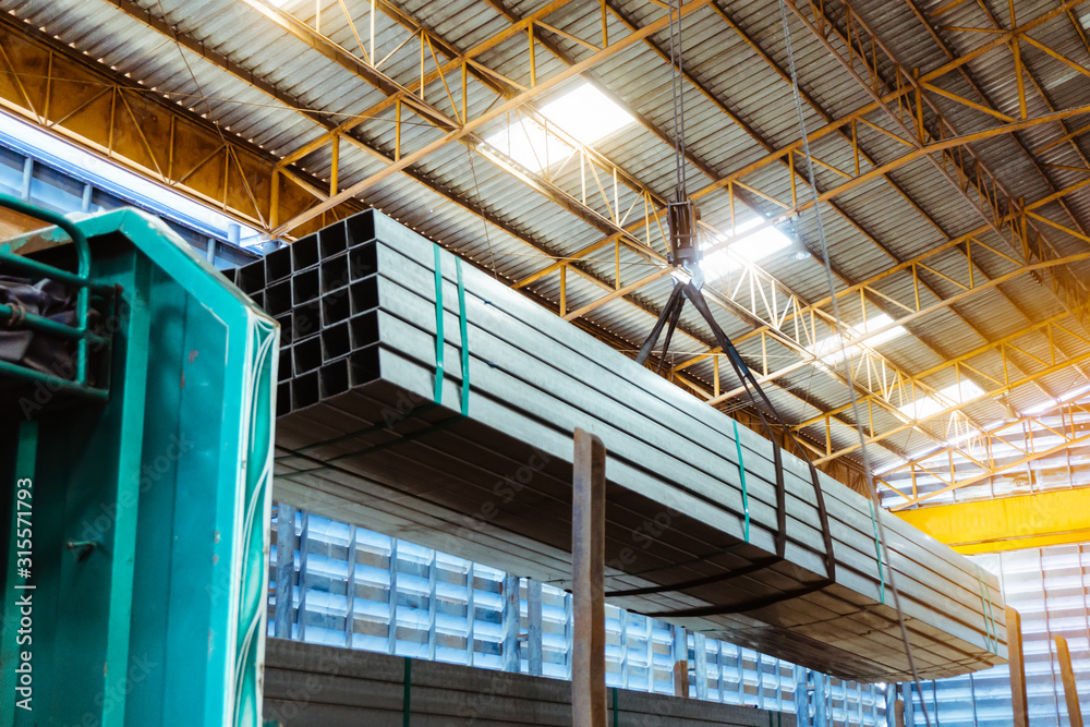 Obraz premium Electric Cable Hoist , heavy hoist iron hook lifting of Steel Pipes bunch and place on a truck at warehouse