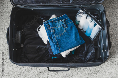 Cuadro en lienzo packing light for a holiday concept, luggage with pile of clothes next to transp