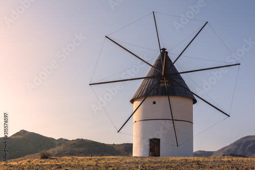 Windmill at sunset between the hills of the natural park of Cabo de Gata in southern Spain. Almeria, Andalucia. Mediterranean Sea