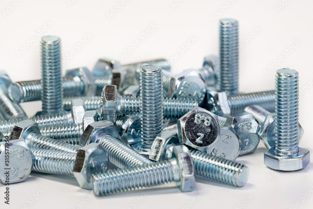 Metal chrome bolts with threads are scattered in the form of a destroyed building on a completely isolated background. Macro photography, copying space. Place for the inscription. Metal chrome bolts with threads are scattered in the form of a destroyed building on a completely isolated background. Macro photography, copying space. Place for the inscription.