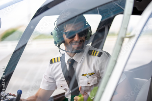 Quadro em tela Confident smiling pilot wearing ear muff sitting in cockpit