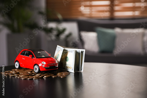 Miniature automobile model and money on table indoors  space for text. Car buying