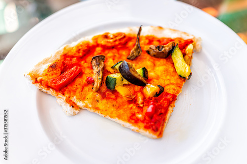Closeup above macro view of pizza slice on white plate in Italy with vegan food tomato sauce chopped zucchini vegetables and mushrooms