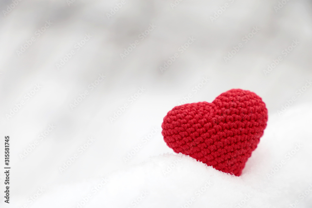 Valentine heart in winter forest. Red knitted heart, symbol of romantic love in the snow, concept of Valentines day