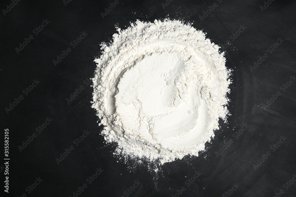 Pile of flour on black table, top view