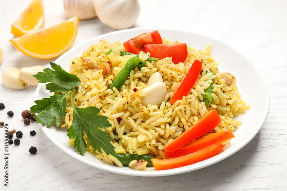 Tasty rice pilaf with vegetables on white wooden table, closeup