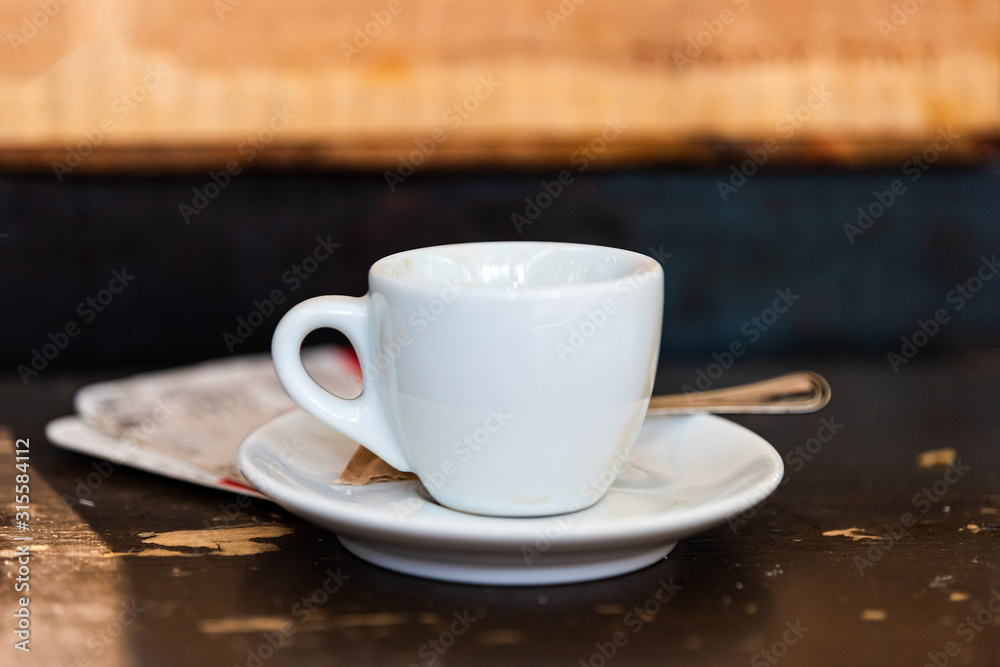 Macro closeup of espresso cappuccino coffee cup on plate saucer and background table in Italy cafe breakfast Macro closeup of espresso cappuccino coffee cup on plate saucer and background table in Italy cafe breakfast