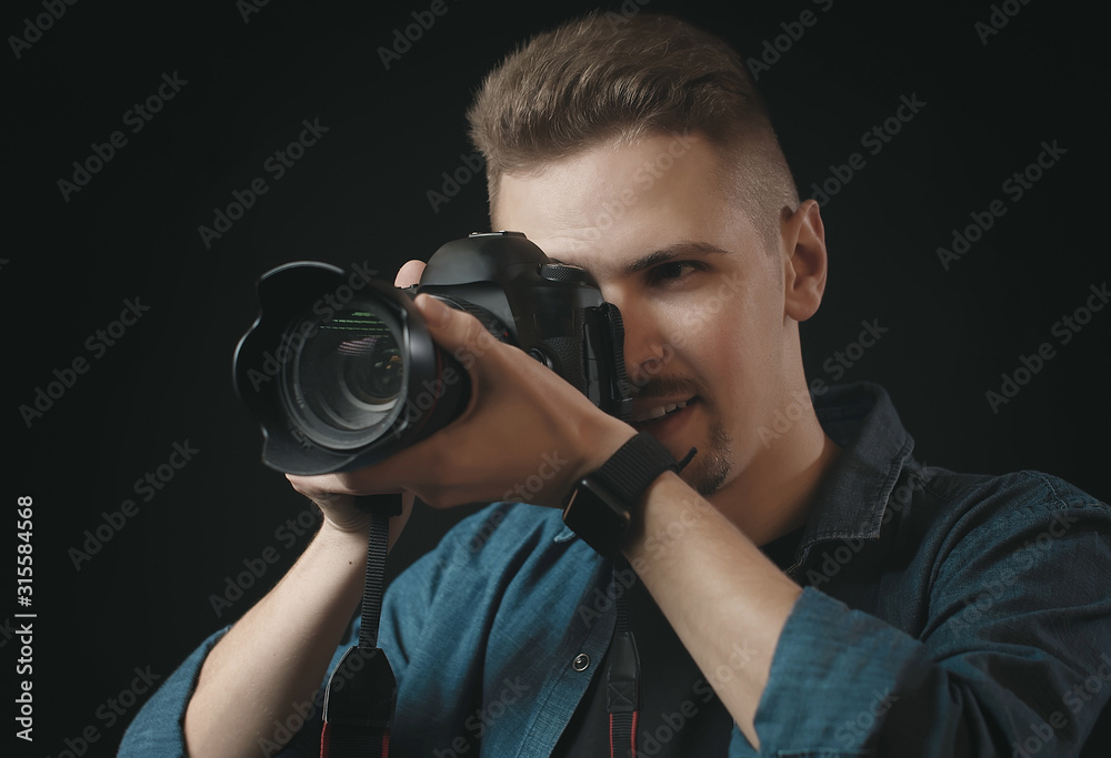 Portrait of photographer holding camera and looking in viewfinder, isolated dark background Portrait of photographer holding camera and looking in viewfinder, isolated dark background