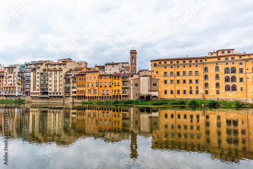 Florence, Italy bell tower orange yellow colorful buildings on Ponte Vecchio by Arno river during summer morning in Tuscany hdr reflection on water