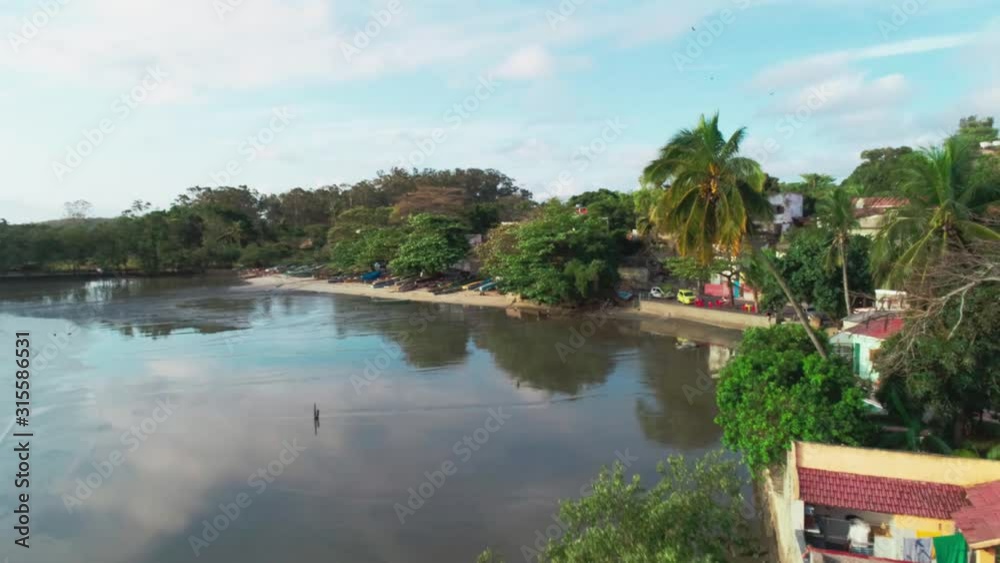Aerial revealing shot of a Polluted Beach in a Fishing Village in Rio de Janeiro, Brazil. Palmtree in the foreground Aerial revealing shot of a Polluted Beach in a Fishing Village in Rio de Janeiro, Brazil. Palmtree in the foreground
