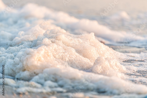 Closeup of sea foam on coast during red tide algae bloom toxic beach in Naples, Florida Gulf of Mexico during sunset on sand © Kristina Blokhin