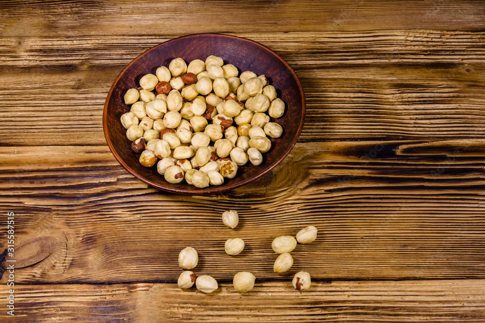 Ceramic plate with peeled hazelnuts on a wooden table Ceramic plate with peeled hazelnuts on a wooden table