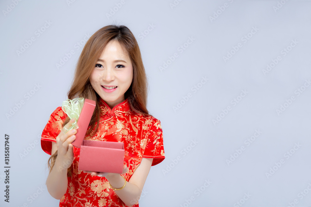 Beautiful portrait young asian woman cheongsam dress smiling holding red gift box on white background, beauty asia girl wear qipao celebrate with exciting, happy Chinese New Year, holiday concept. Beautiful portrait young asian woman cheongsam dress smiling holding red gift box on white background, beauty asia girl wear qipao celebrate with exciting, happy Chinese New Year, holiday concept.