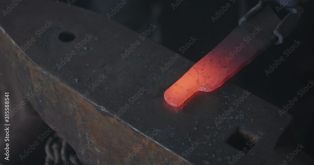 Blacksmith hammering heated iron on anvil making knife dark eerie closeup Blacksmith hammering heated iron on anvil making knife dark eerie closeup