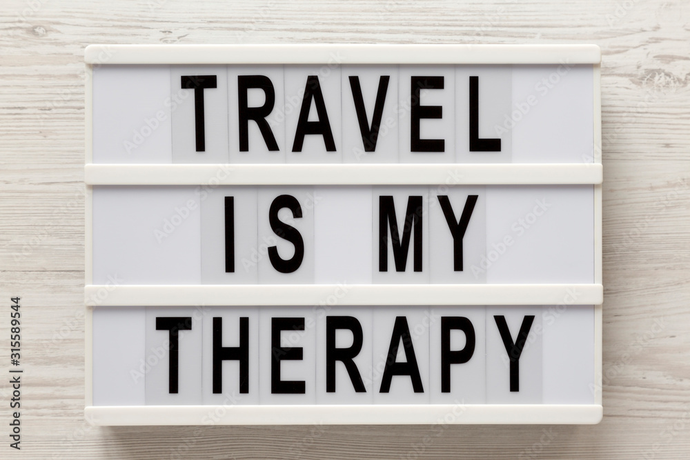 'Travel is my therapy' words on a lightbox on a white wooden background, top view. Overhead, from above, flat lay. 'Travel is my therapy' words on a lightbox on a white wooden background, top view. Overhead, from above, flat lay.