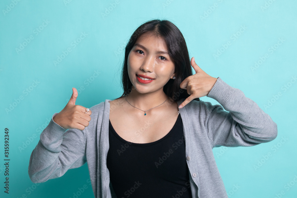 Fototapeta premium Young Asian woman thumbs up show with phone gesture.