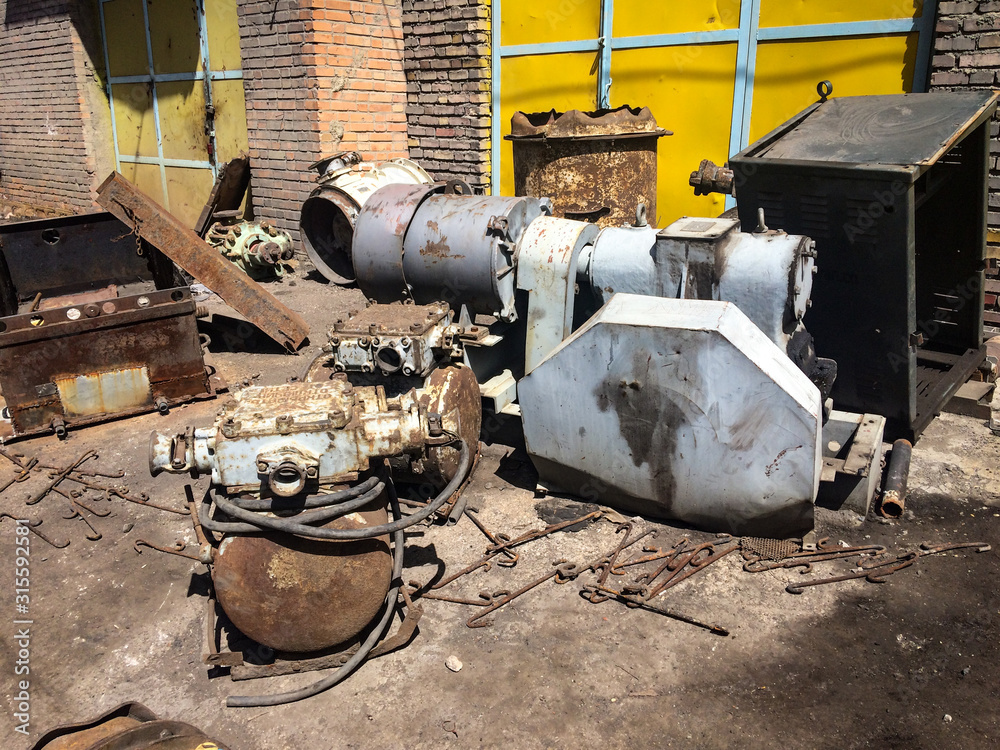 Corroded and rusted iron. Damaged factory. Unused equipment on the ground.