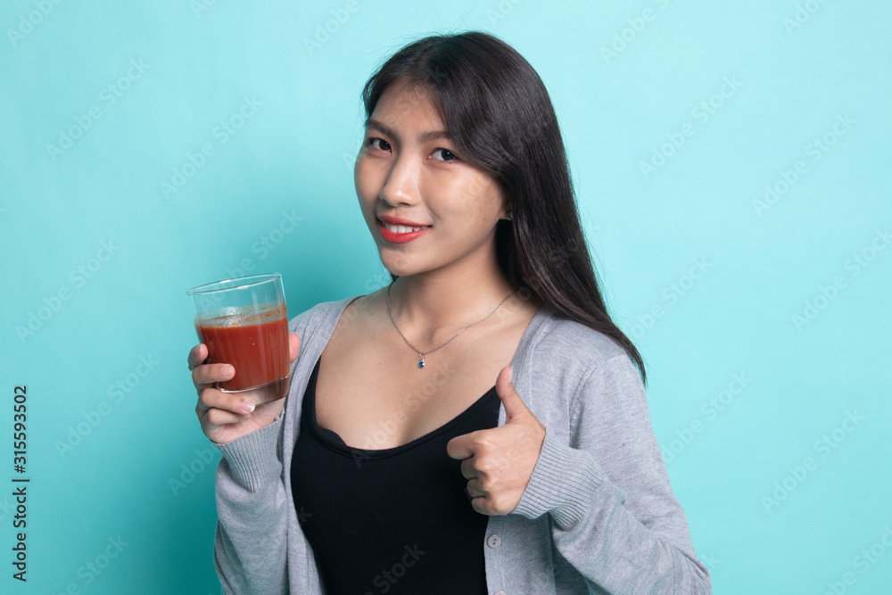 Young Asian woman thumbs up with tomato juice. Young Asian woman thumbs up with tomato juice.