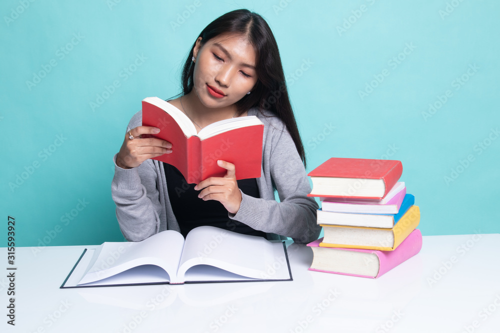 Young Asian woman read a book with books on table. Young Asian woman read a book with books on table.