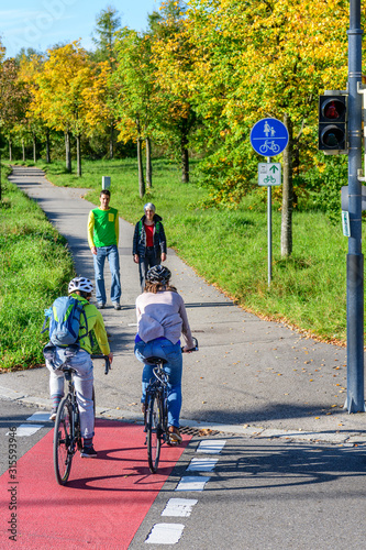 Radfahrer fahren vom Radweg auf einen kombinierten Rad- und Gehweg mit Fußgängern photo