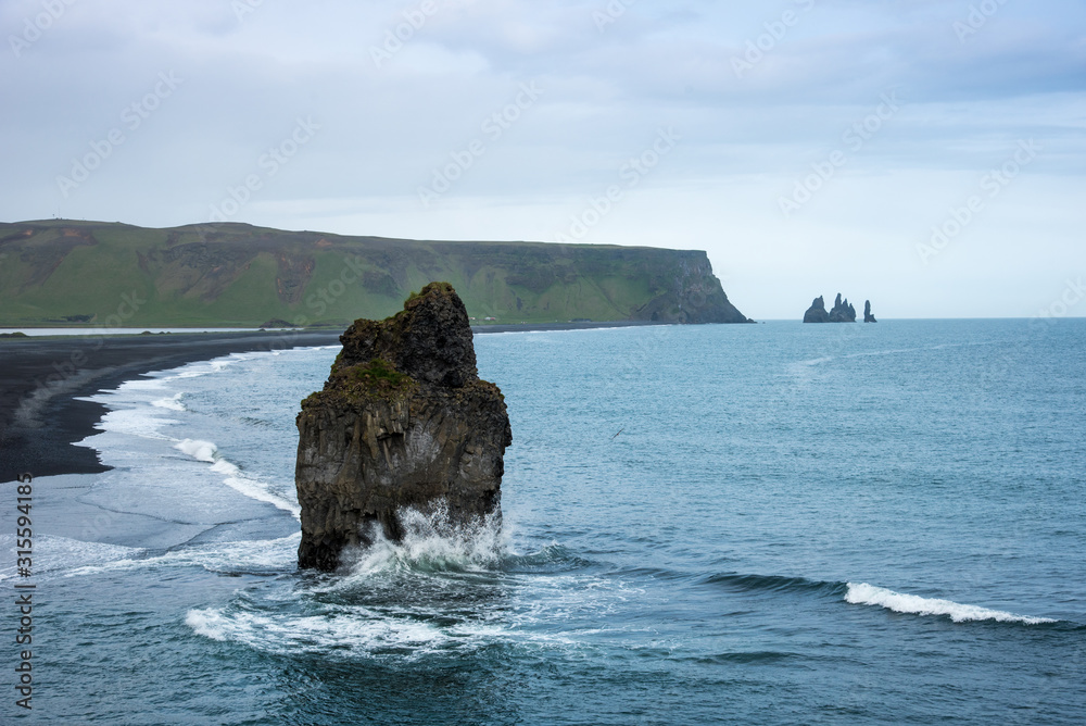 Magical amazing dramatic scenic landscape with big alone stone in the middle of the ocean nearby Reynisdrangar Sea Cliffs, near cape Dyrholaey and Vik, Iceland. Exotic countries. Amazing places.