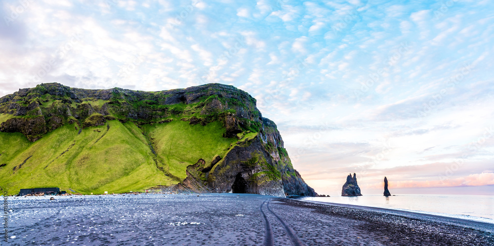 Beautiful dramatic landscape with cave in basalt rock on the black sand beach on Reynisdrangar Sea Cliffs, stones called Troll under the Reynisfjall Mountain near Vik, Iceland. Exotic countries.