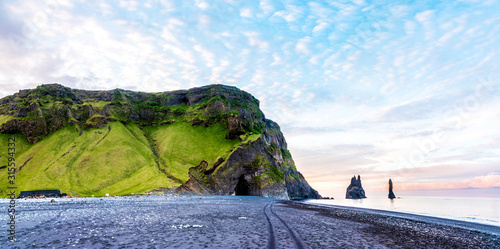 Beautiful dramatic landscape with cave in basalt rock on the black sand beach on Reynisdrangar Sea Cliffs, stones called Troll under the Reynisfjall Mountain near Vik, Iceland. Exotic countries.