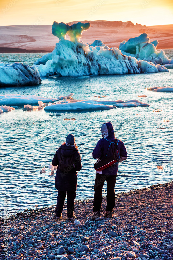 Young couple looking at beautiful landscape with depths of ice in the famous Jokulsarlon glacial lagoon in Iceland. Exotic countries. Amazing places. Popular tourist atraction.
