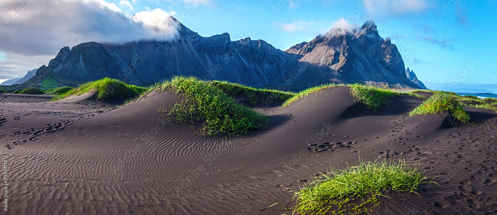 Scenic landscape with most breathtaking mountains Vestrahorn on the Stokksnes peninsula and cozy lagoon with green grass on the sand dunes in Iceland. Exotic countries. Amazing places.
