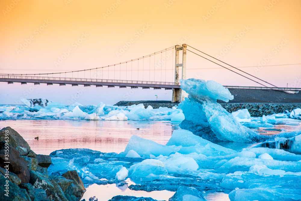 Iceberg parts float to the ocean under a bridge in the bay in the famous Jokulsarlon ice lagoon in Iceland. (global warming, greenhouse effect - concept)