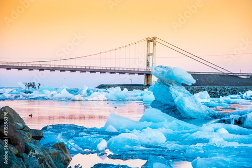 Obraz na płótnie Iceberg parts float to the ocean under a bridge in the bay in the famous Jokulsarlon ice lagoon in Iceland. (global warming, greenhouse effect - concept) w salonie