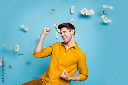 Photo of excited ecstatic crazy shouting manager having received salary payment wearing yellow shirt saying yes isolated over pastel color blue background