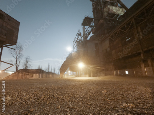 Old closed industrial ironworks at night. Epic metal structures and chimneys lit by the moon