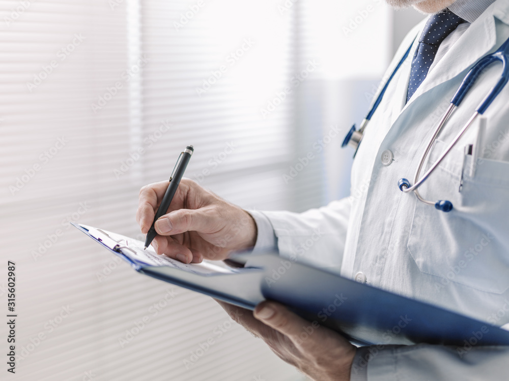 Doctor writing a medical prescription on a clipboard Doctor writing a medical prescription on a clipboard