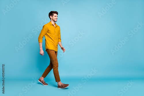 Turned full length body size photo of attractive man going towards his workplace wearing shoes smiling toothily beaming isolated over blue pastel color background