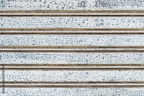 Cracked white paint colors on stripe pattern of metallic roller shutter doors or rolling steel doors background.