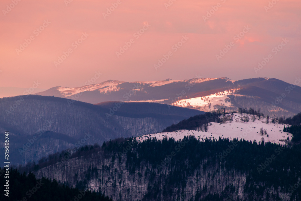 Mountain range with visible silhouettes through the morning colorful fog.Tarcu Mountains in Romania.