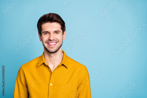 Photo of handsome creative executive director wearing yellow shirt smiling toothily isolated over blue pastel color background © deagreez