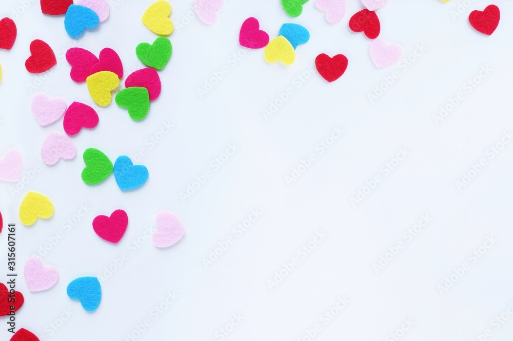 Colored small hearts on a white background. The concept of Valentine's Day, love, color therapy. Top view, flat lay with copy space for text.
