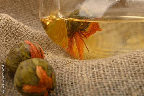 Flower tea brewed in a glass teapot and flower tea balls on a background of rough homespun fabric. Close up. photo