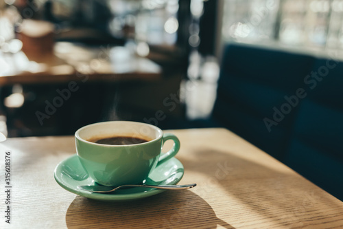 Cup of morning coffee on a wooden table in a cafe.