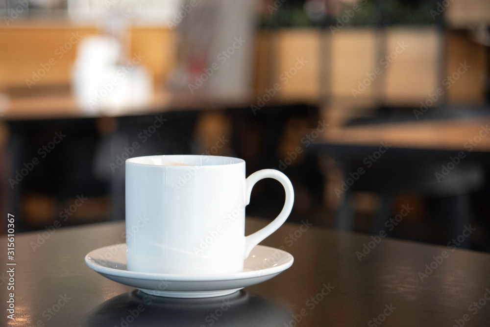 A close up of a white coffee cup with smoke on a wooden table
