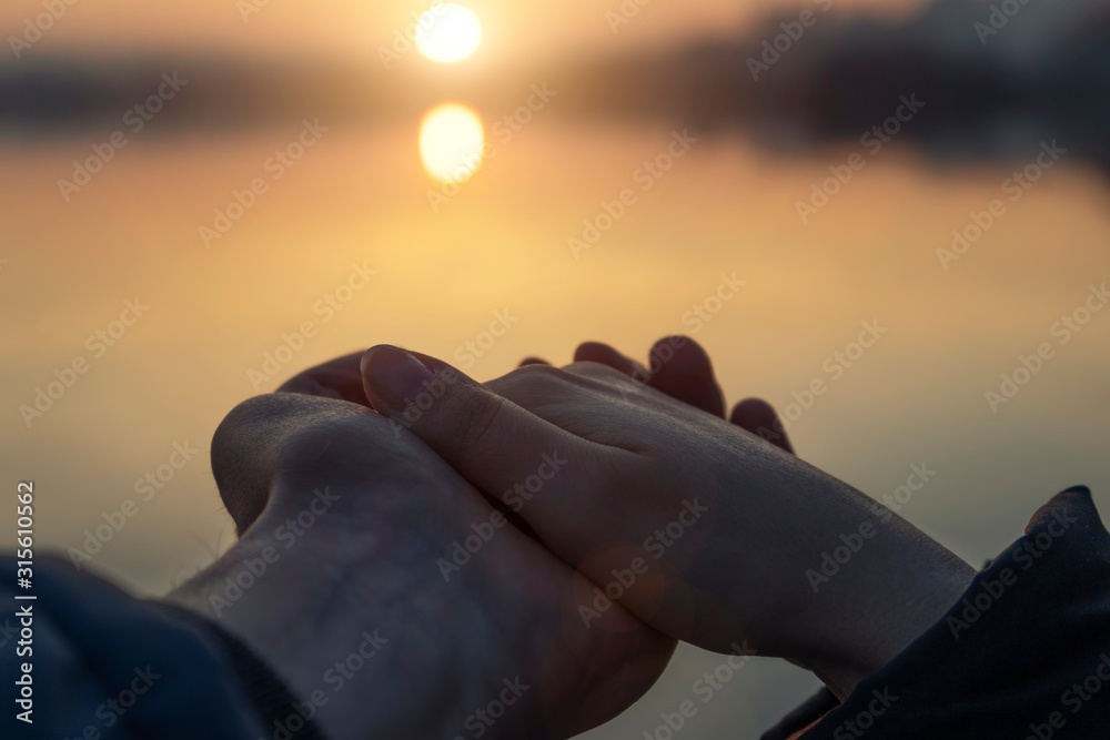 Guy and girl hold each other's hands at sunset