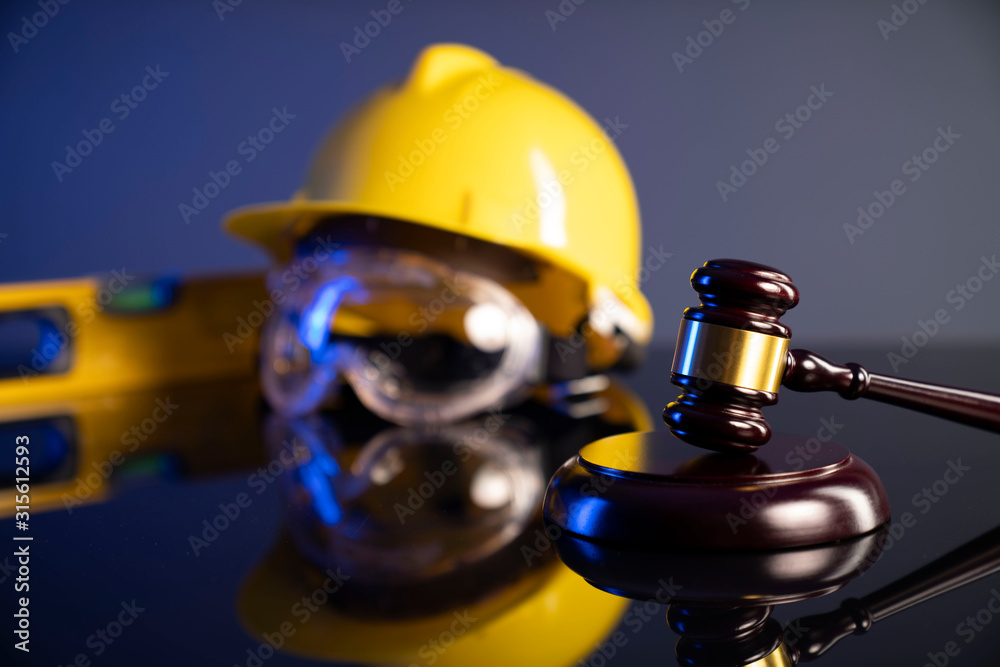 Construction law. Helmet and gavel on the blue background.