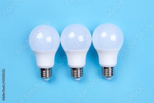 Three LED bulbs on blue background. Saving energy concept. Ftat lay. Top view. photo