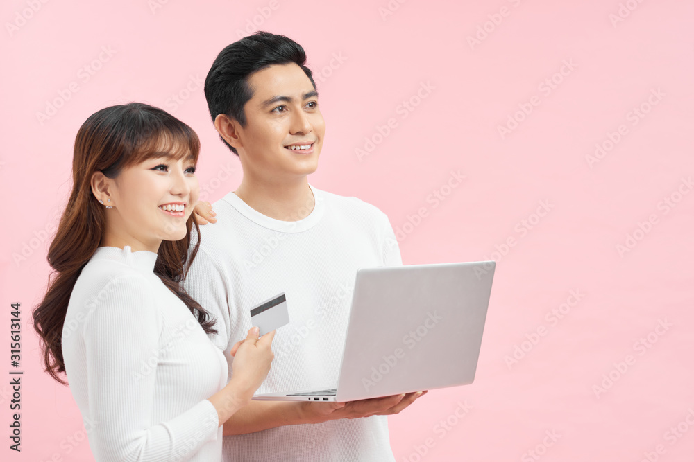 Excited young couple shopping online, holding credit card and looking at laptop Excited young couple shopping online, holding credit card and looking at laptop