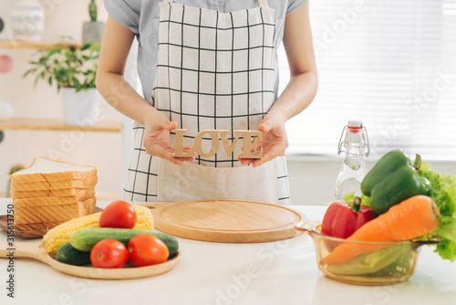 Culinary concept. Woman holding wooden letter LOVE, cooking healthy dinner