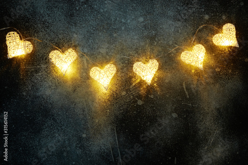 Fototapeta Naklejka Na Ścianę i Meble -  Beautiful heart-shaped fairy lights glowing on dark . St. Valentine's Day background